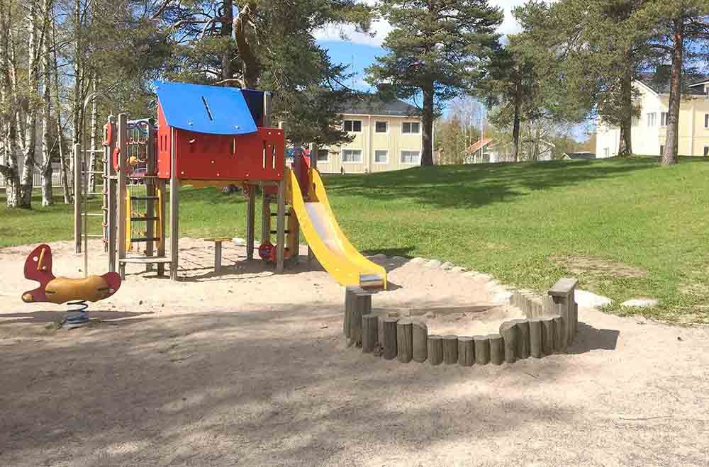 Klättertorn med rutschkana och liten lekgunga. Underlaget är sand.