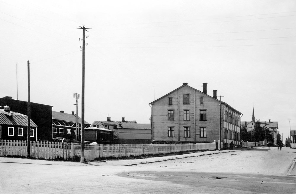 Vy över gatukorsning med trähus i staden.