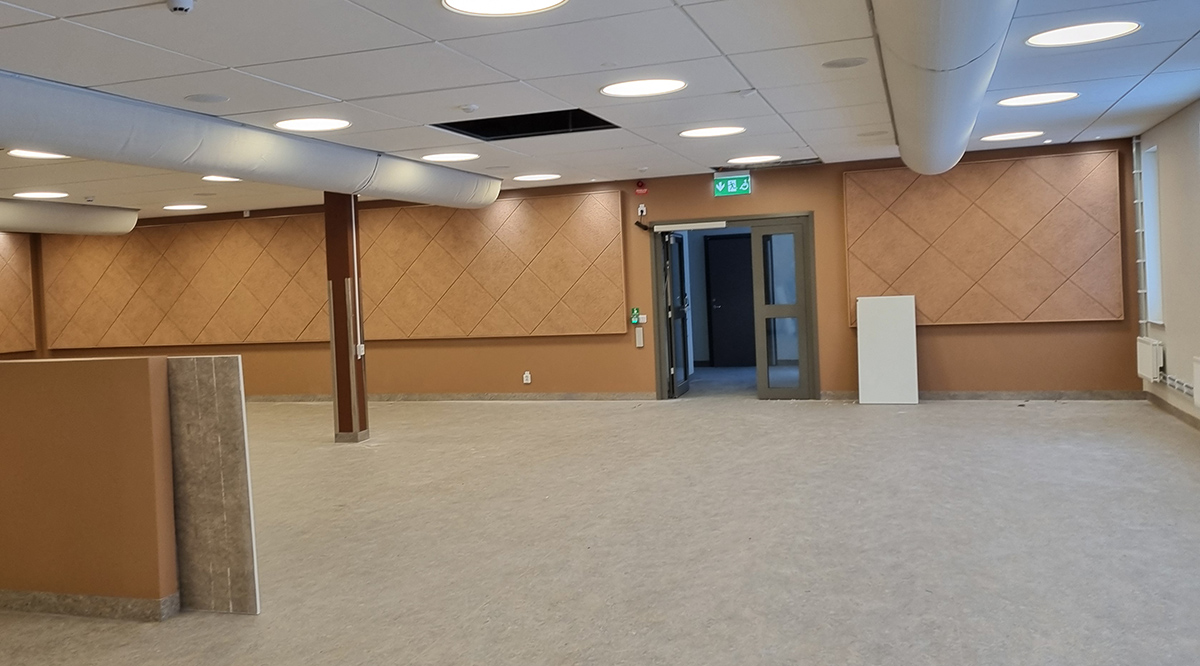 En tom lokal där bort med ätande barn snart ska få plats. Bruntonade ljudabsorbenter sitter på väggarna